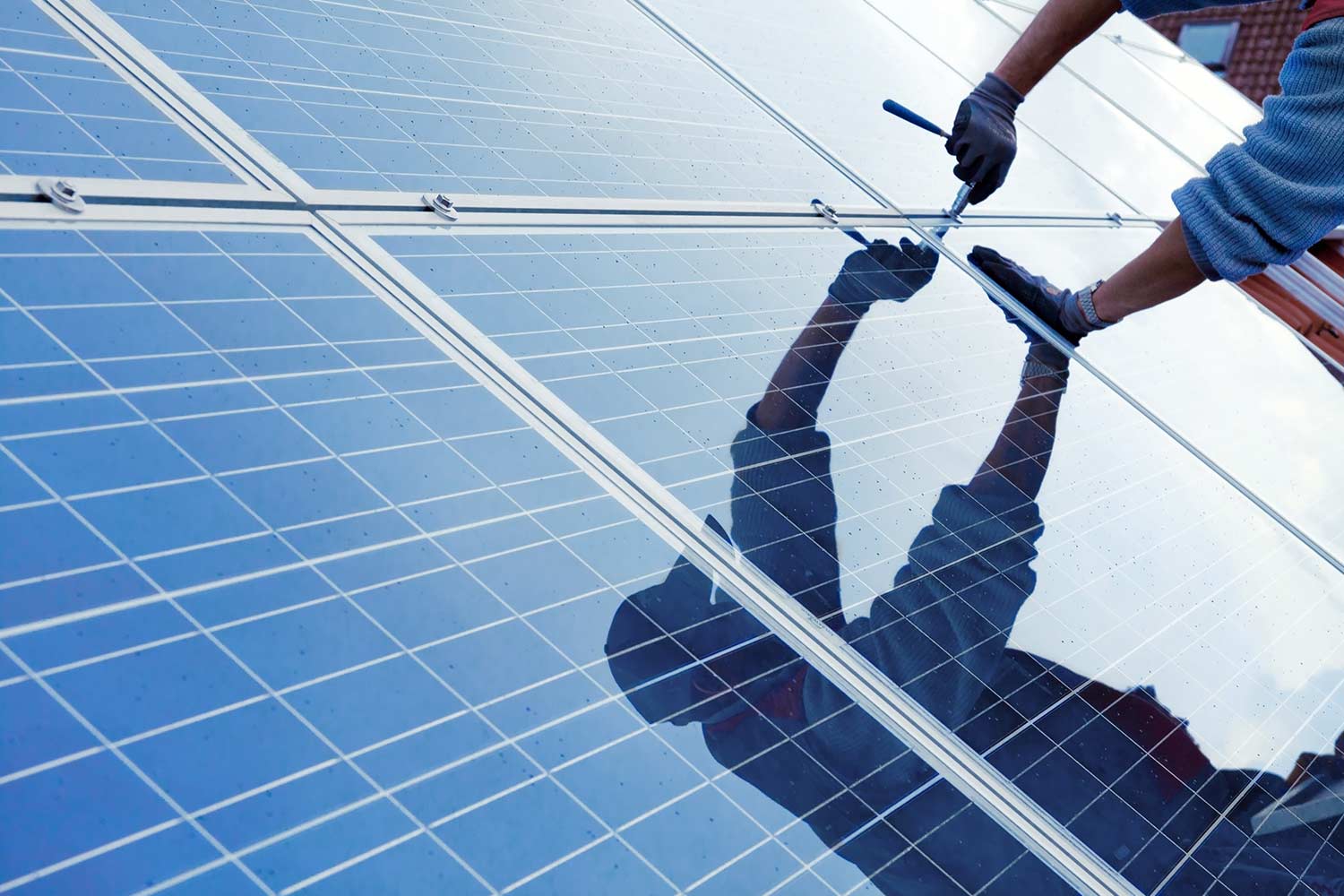 Handwerker installiert Solarplatten auf Hausdach